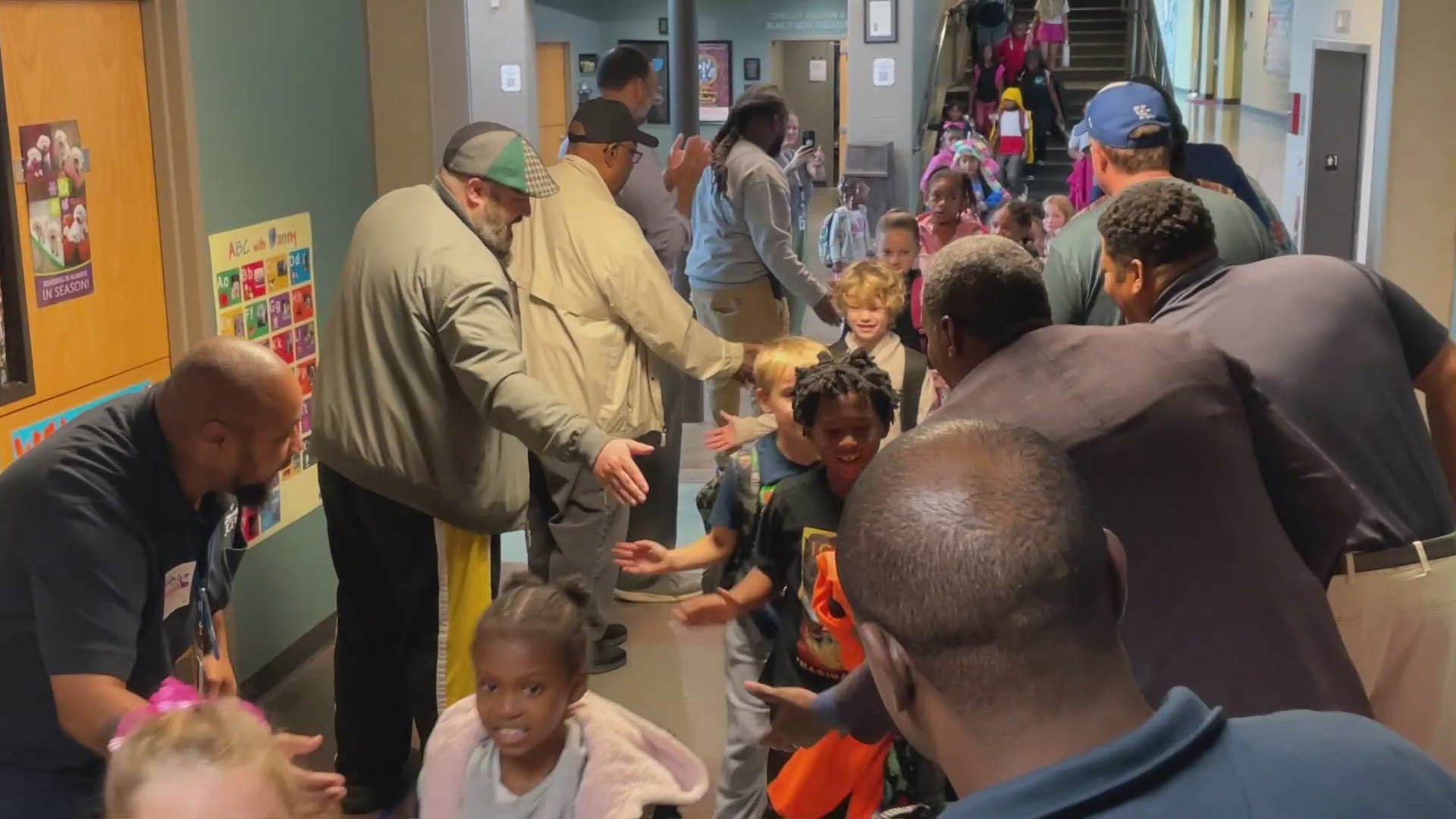 Adult male figures gathers at Lincoln Elementary School to welcome students to school Wednesday morning.