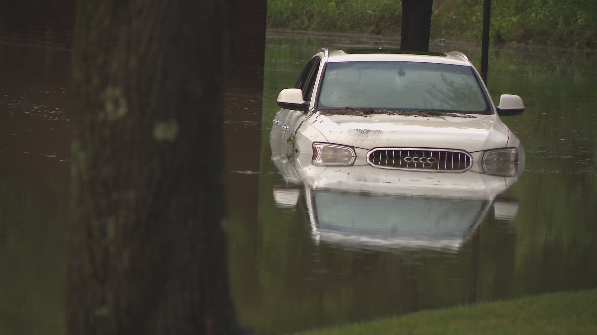 In one part of the area, two cars are partially submerged and another is almost completely underwater.