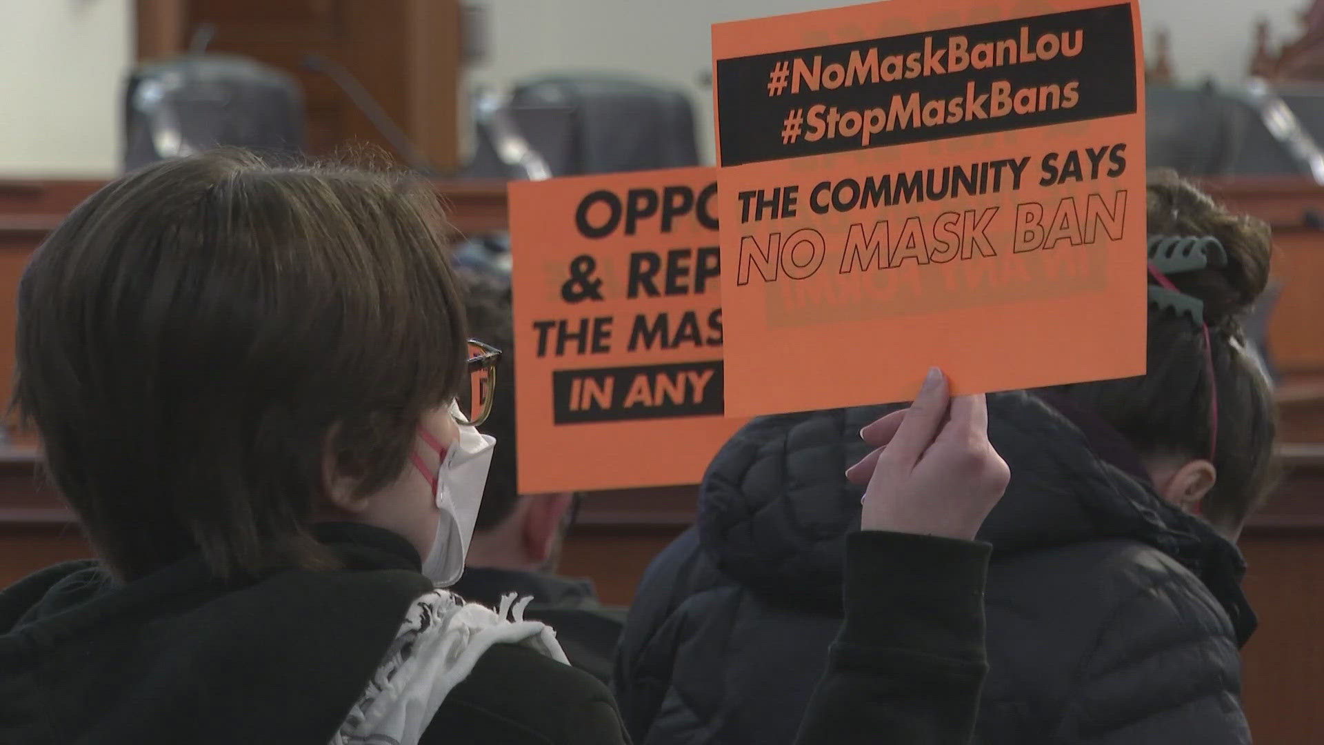 Protestors raised signs in opposition to the ban in the Metro Council chambers on Wednesday.