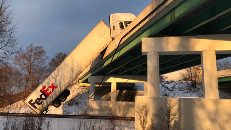 FedEx semi-truck slides off Indiana bridge, dangles over railroad tracks